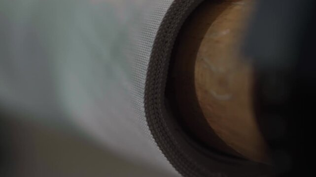 Roll of corset fabric unwinding on machine spindle during textile production