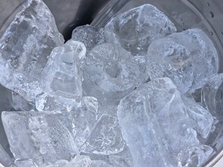 Obraz premium A close-up, high-angle view of large, translucent, irregularly shaped ice chunks inside a metallic container, creating a texture of frozen surfaces.