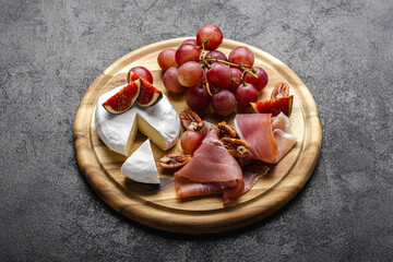 Appetizer board with meat, cheese, grapes, nuts and fresh figs.