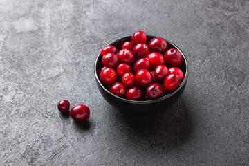 Cranberries in black bowl on dark stone background