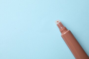 Beautiful nude lip gloss on light blue background, top view. Space for text