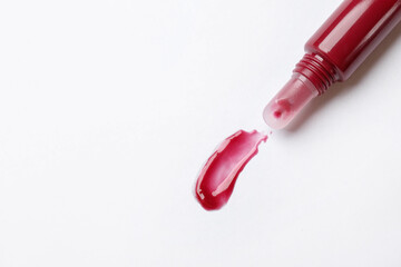 Beautiful dark red lip gloss with swatch on white background, top view. Space for text