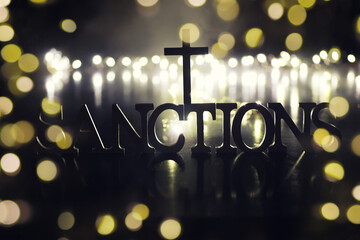 word sanctions spelled in letters on table made of wooden block letters with dramatic lighting and...