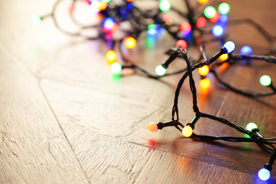 Bright Christmas lights on wooden table, closeup. Space for text