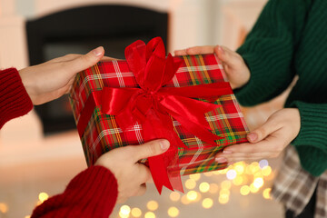 Merry Christmas and Happy New Year. Woman giving gift box to her friend indoors, closeup