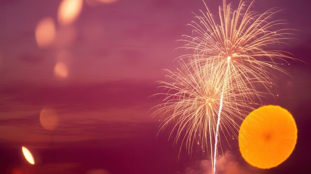 Bright golden fireworks explode against a dark purple sky with soft bokeh lights