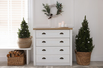 Stylish room with cabinet, small spruce trees and Christmas decor. Interior design