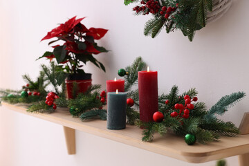 Burning candles and Christmas decor on shelf indoors, closeup. Interior design
