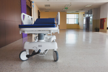 A medical gurney with an IV pole in a bright hospital corridor.