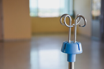 A medical IV pole in an empty, bright hospital hallway.