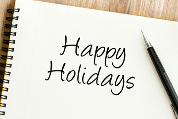 A heartfelt Happy Holidays message written on a white notepad with a pen, perfect for festive greetings and seasonal joy