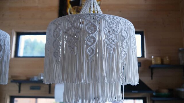 Large macrame pendant light hanging in a wooden room with windows and shelves