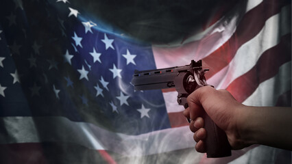 Human hand holding a revolver handgun in front of a USA flag background. Concept of gun violence