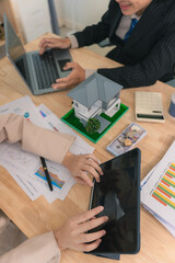 Asian couple discusses real estate purchase, model home with contract documents, negotiations,...