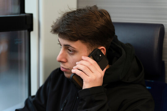 Young man talking on phone while commuting by train