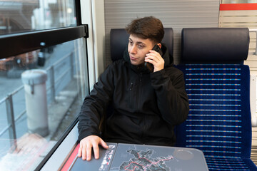 Young man making phone call travelling by train
