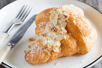 Delicious french almond croissant on white plate, closeup view. Sweet puff pastry