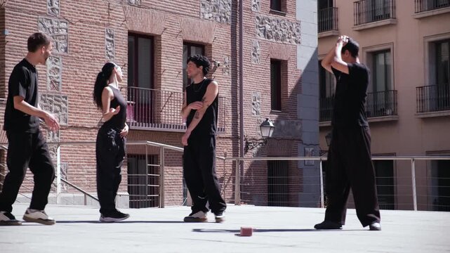 Four talented dancers in black outfits executing a synchronized modern dance choreography in a city square