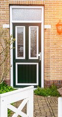 Facade of typical Dutch door house with brick walls, steps, front door windows. Doors on the street, Netherlands
