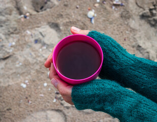 A woman is holding a cup of tea in hands. 