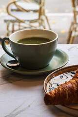 a green cup of matcha tea and croissant