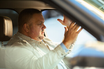 Adult man frustrated and gesturing while driving in car