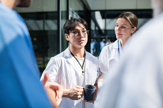 Young adult doctors in focused discussion on hospital courtyard