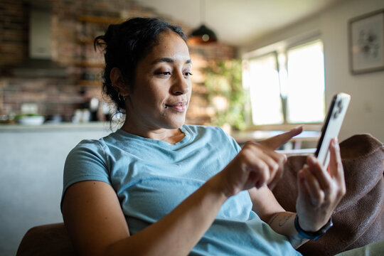 Young adult woman relaxed and focused on smartphone at home