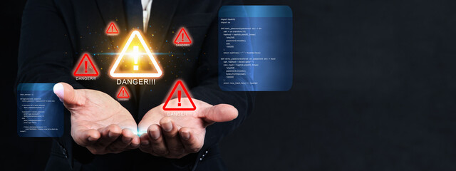 Businessman interacting with a digital warning triangle interface on a computer, highlighting...
