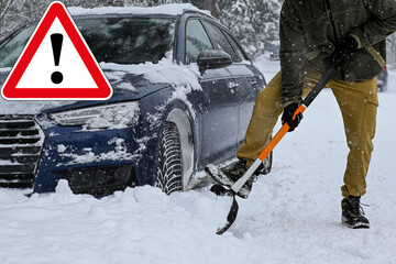Driver clearing snow to free a stuck car on a winter road with a warning triangle overlay