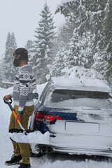 Man clearing accumulated snow from a blue vehicle after a heavy snowfall