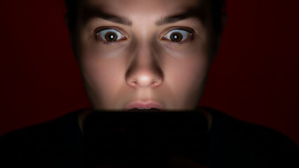 Intense gaze of a woman captivated by a glowing screen in darkness, illustrating the profound impact and potential addiction of digital content