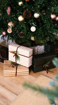Decorated Christmas tree with wrapped presents underneath on a wooden floor with festive lights.