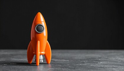 Orange Toy Rocket Standing Upright on Dark Surface with Black Background