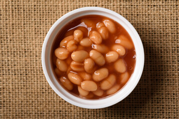 Baked beans from canned food on brown background