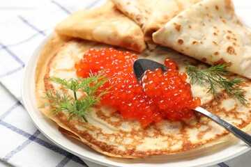 Tasty crepes with red caviar on table, closeup