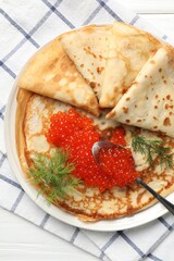 Tasty crepes with red caviar on white wooden table, top view