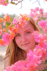 Fototapeta premium Woman gently smelling bright bougainvillea flowers outdoors on a sunny day, enjoying a calm and natural moment.