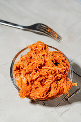 a bowl of shredded pulled pork with a metal fork