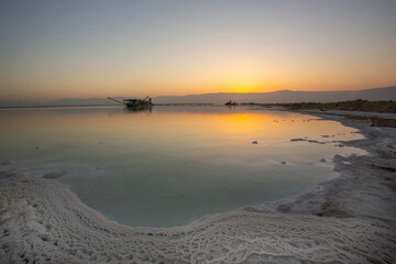 Abstract, high-contrast view of the Dead Sea shoreline, featuring intricate, crystalized white salt...