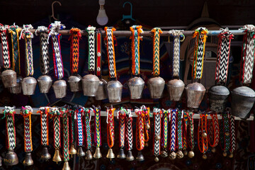 Colorful handcrafted bells and decorative strings displayed in a vibrant market