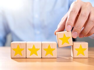 Hand adding a wooden block with a star customer satisfaction concept rating and review