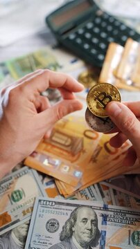 Hands shows silver and golden BTC bitcoin against the dollars and euros