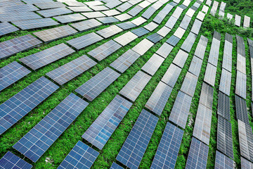 Aerial view of solar panels arranged in rows on the green mountain slope.