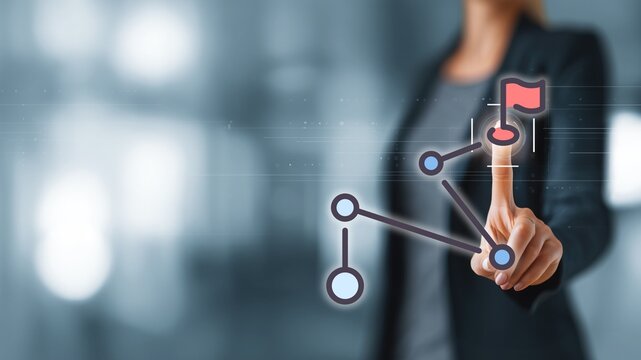 Businesswoman touching network node with flag icon via finger, connected nodes in office setting. Concept of goal achievement, network connection, business strategy and digital target tracking - Powered by Adobe