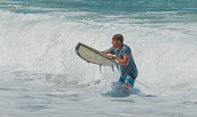 Young surfer walk with surfing boards on the beach in Brazil