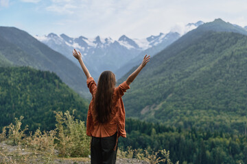 Obraz premium Woman in mountains raising arms for freedom and nature, authenticity inclusivity