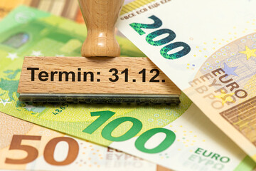 Ein Holzstempel ist beschriftet mit dem Aufdruck Termin: 31.12. als Symbolbild für einen Zeitpunkt...