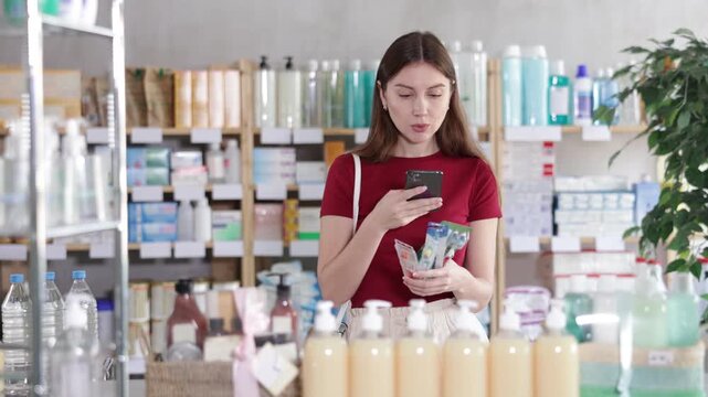 Uncertain young female customer scanning barcode on toothbrush in chemist's shop. High quality 4k footage