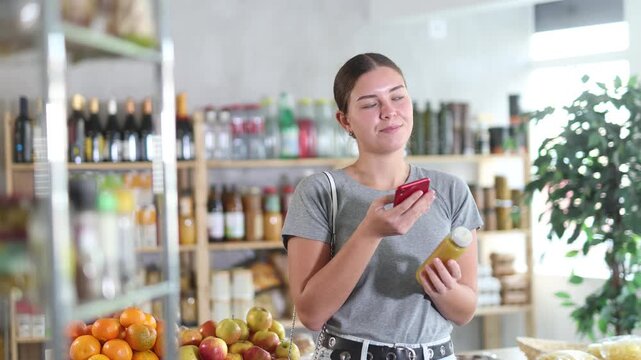 Woman scans the QR code on smoothie bottle on a mobile application. Use of modern methods of online payment by barcode. High quality 4k footage